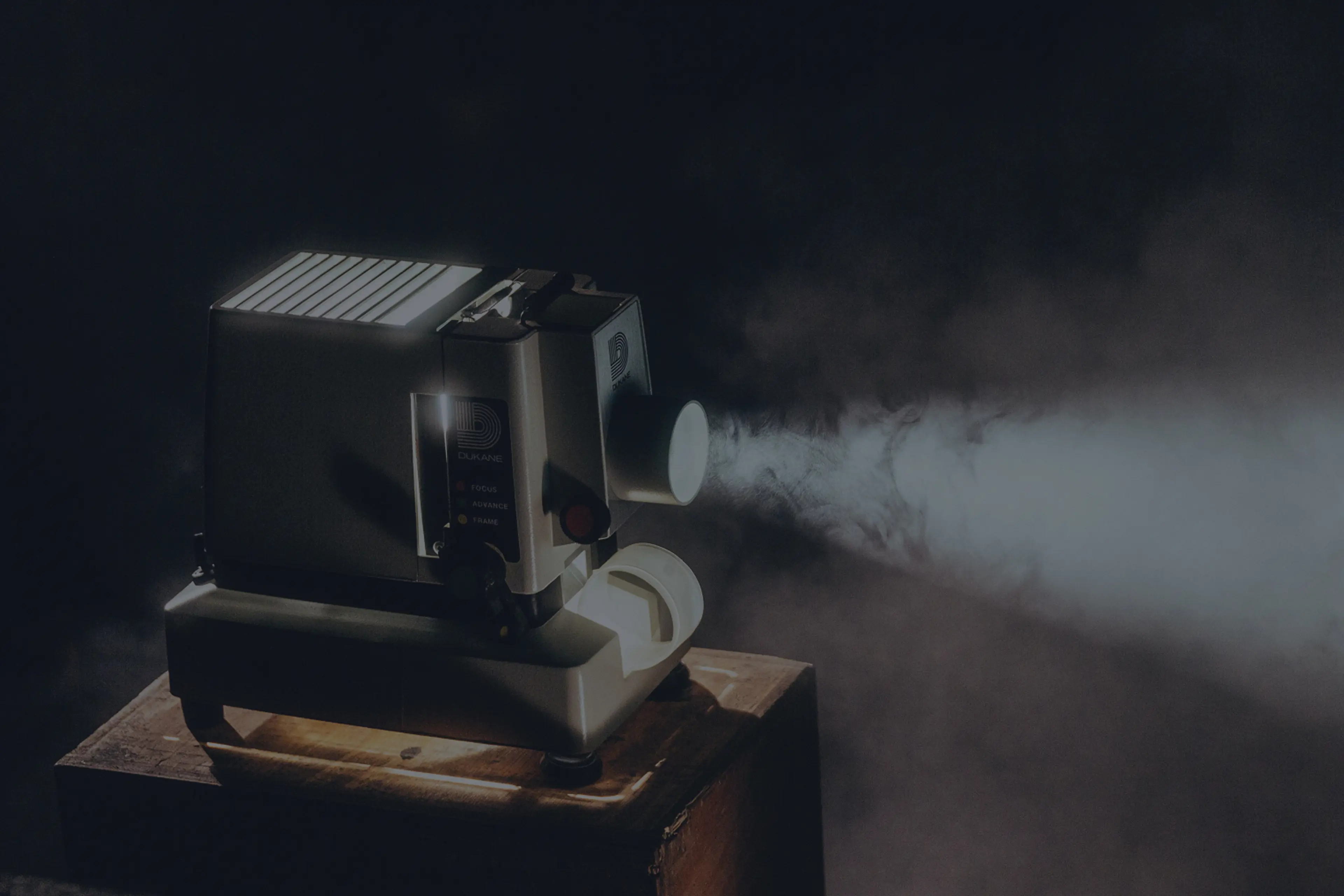 Äldre filmprojektor som projicerar ljus genom rök