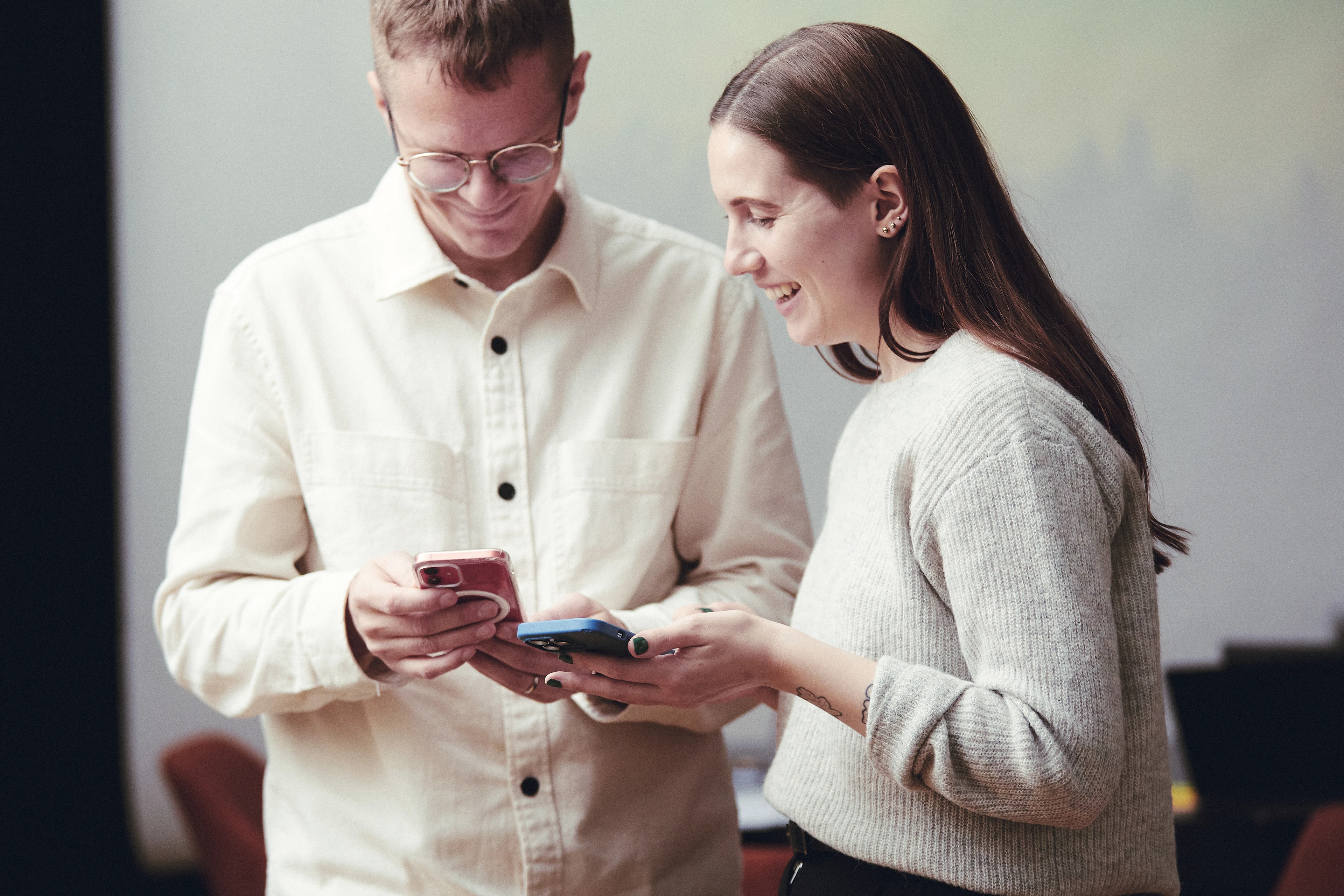 Kvinna och man tittar ner i varsin telefon