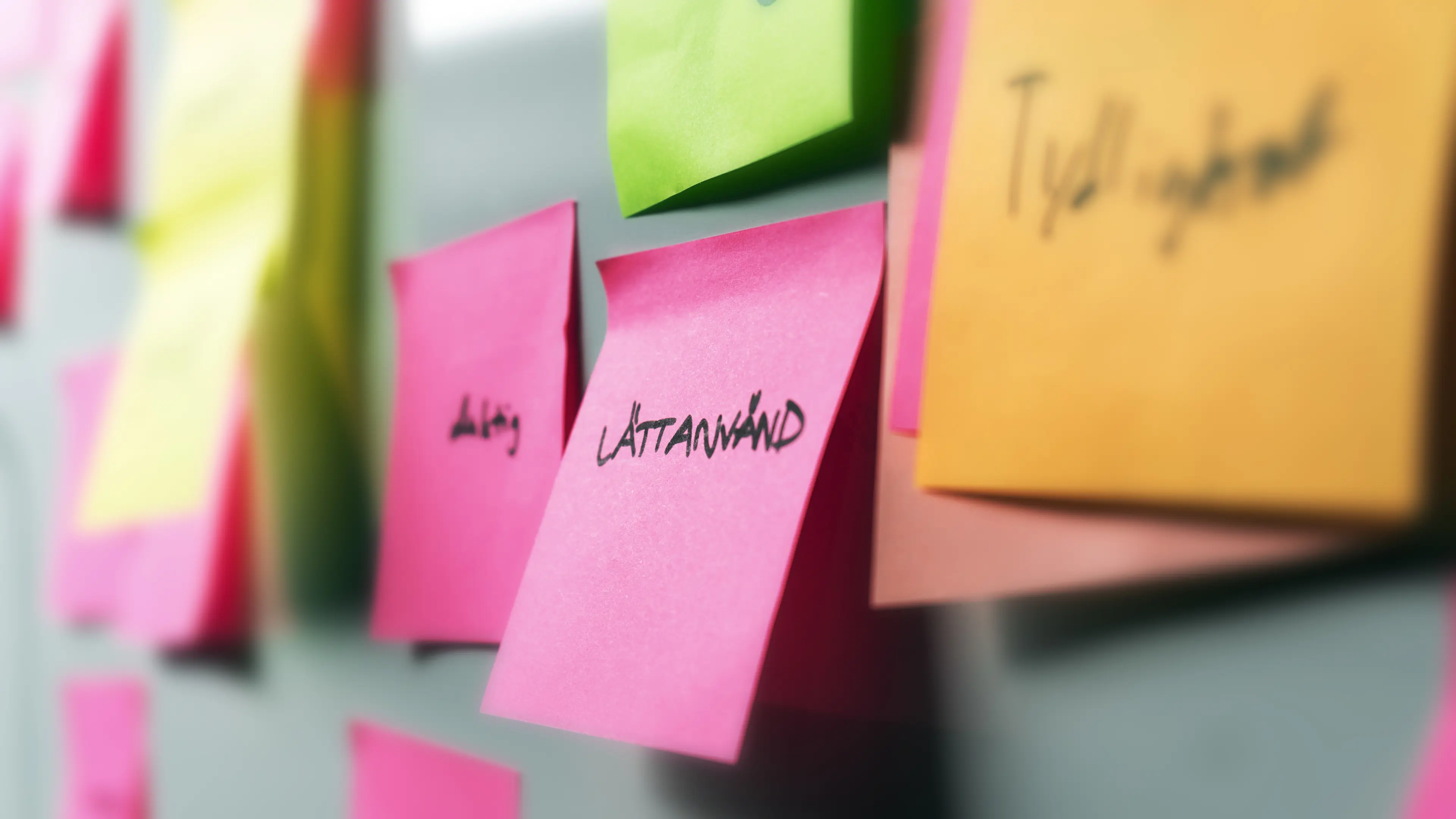 Post it-lapp med texten "Lättanvänd" på en vägg med post it-lappar