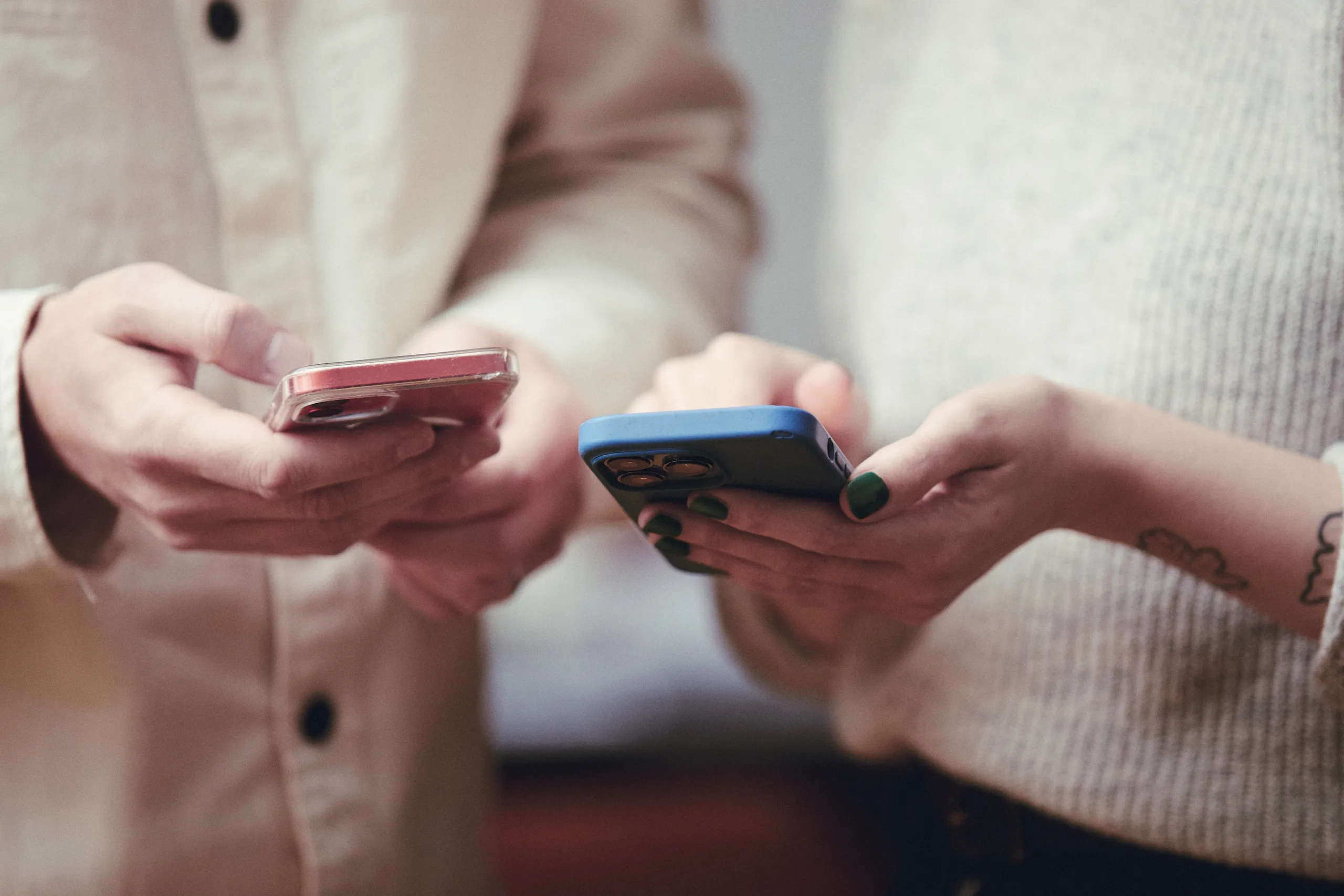 Händer som håller i två mobiltelefoner