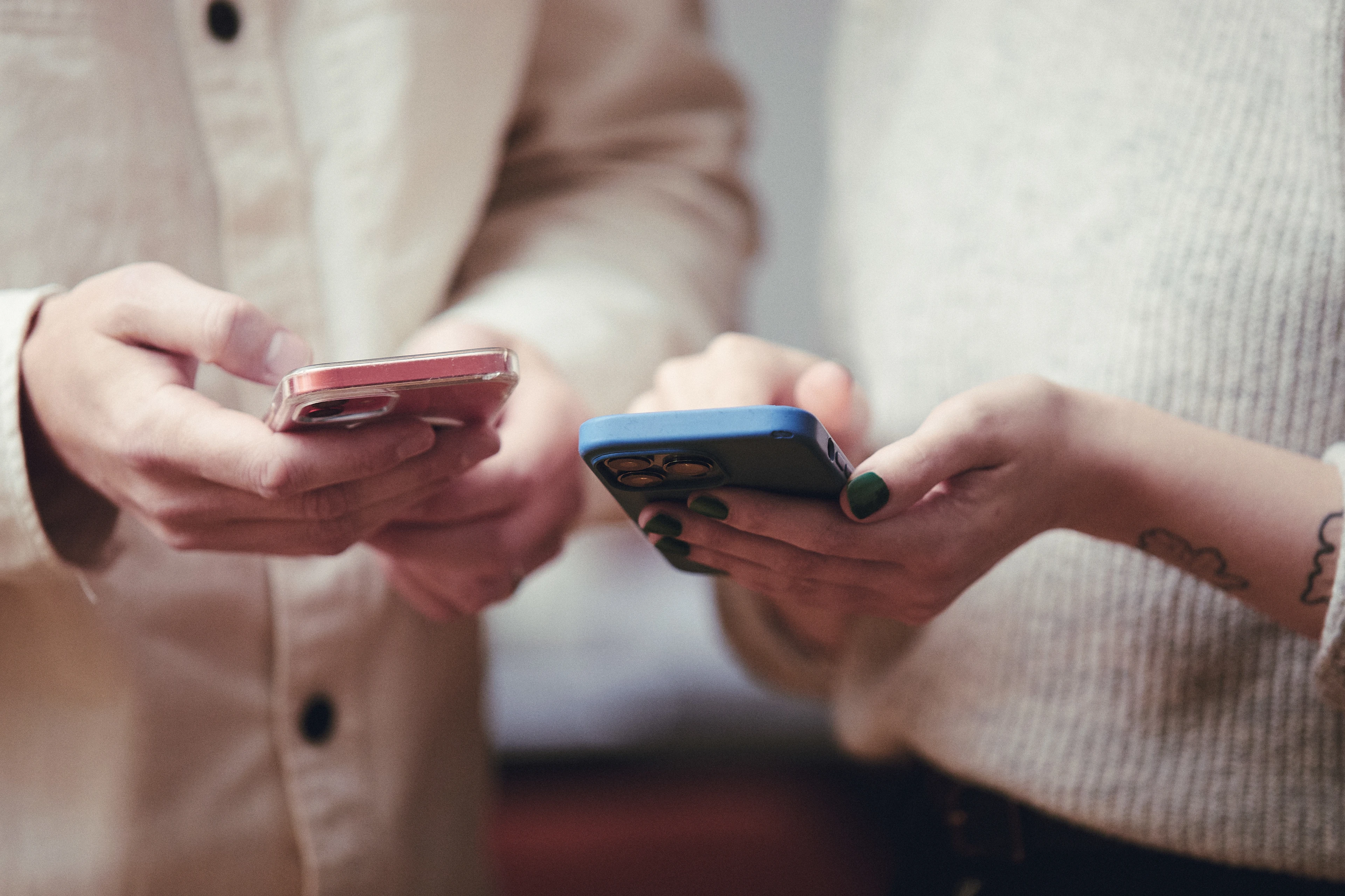 Händer som håller i två mobiltelefoner