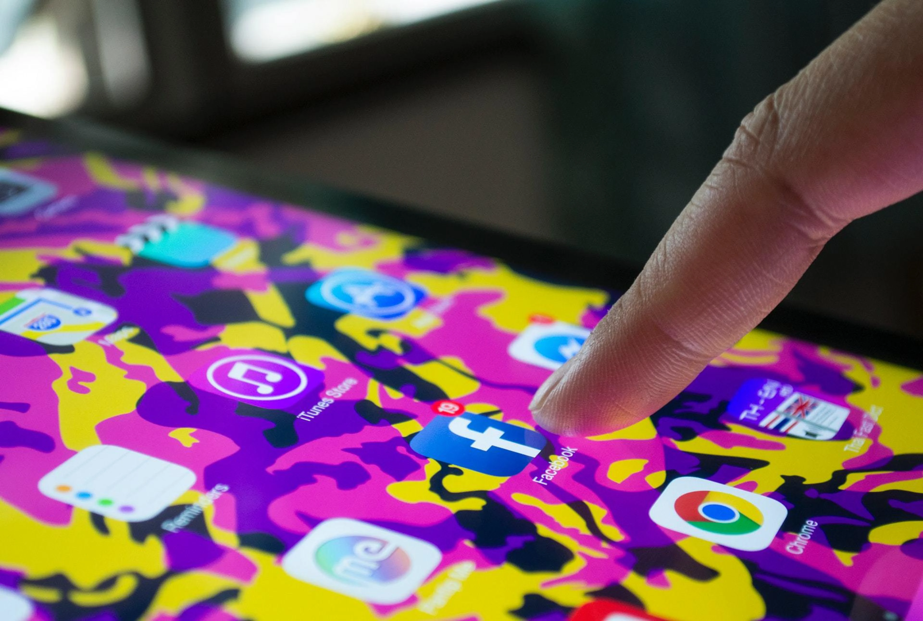 Finger på väg att klicka på facebook-ikon på en skärm